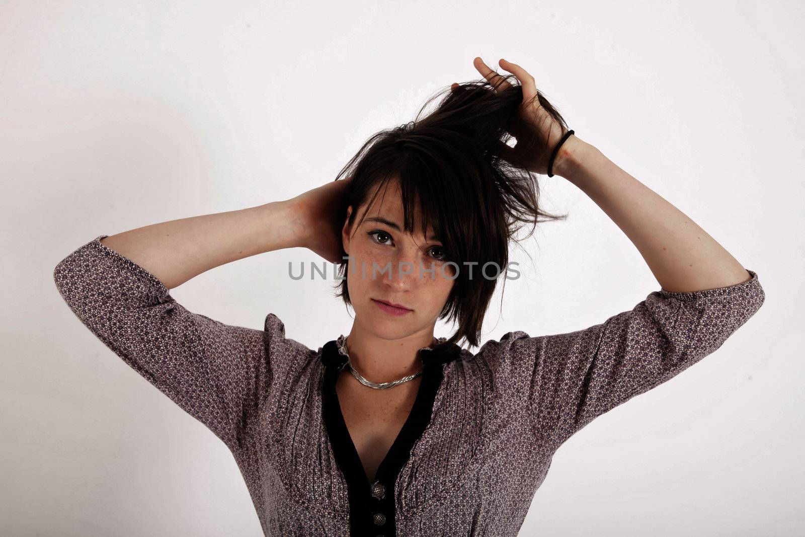 portrait of a young woman in grey dress playing with her hair on studio
