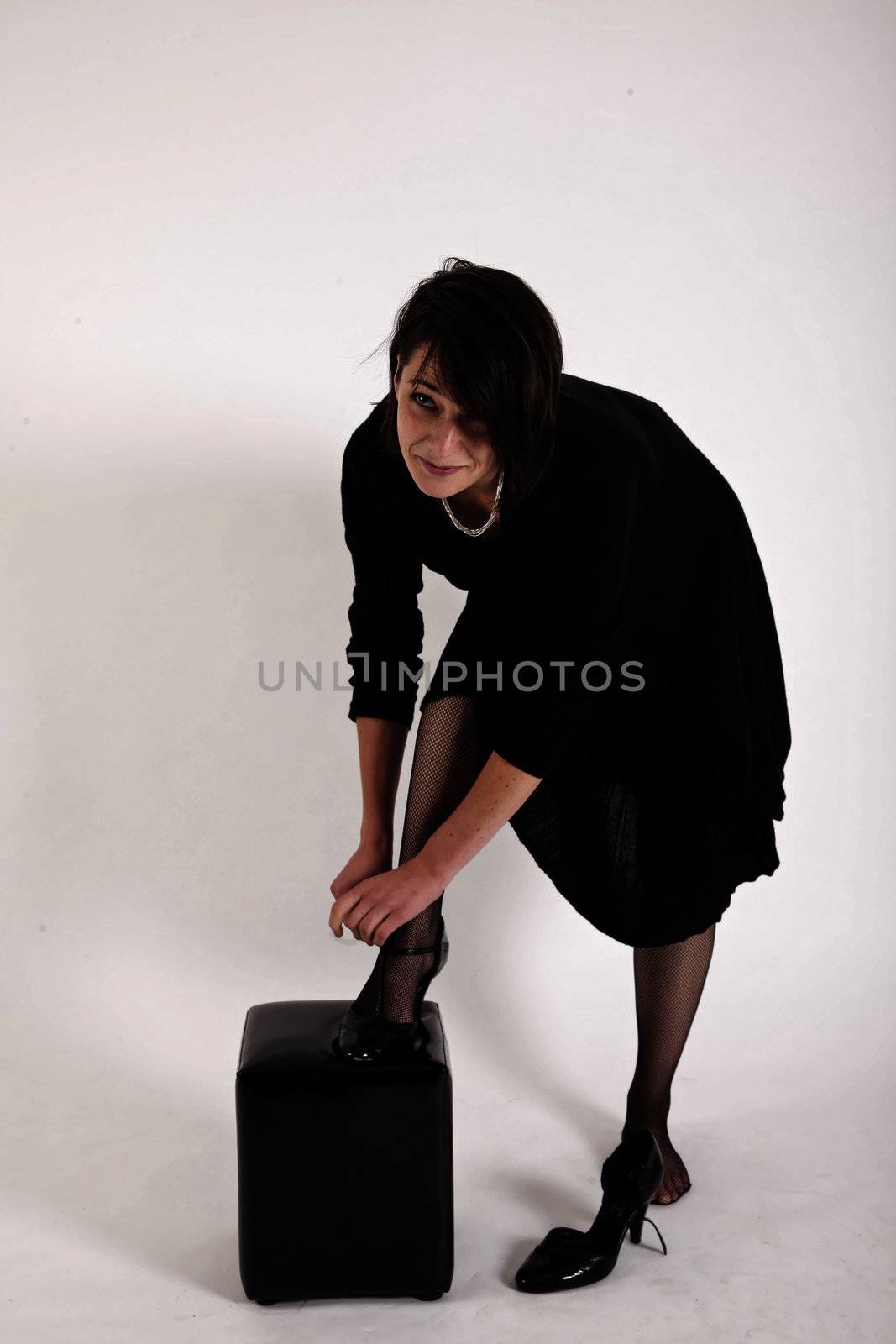 young brunette woman in black dress wearing her shoes by macintox