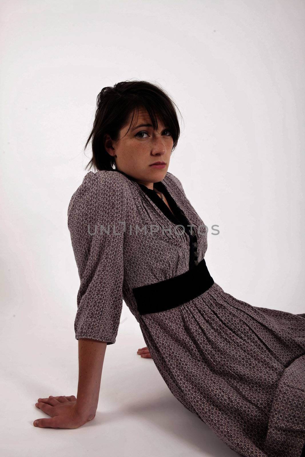 young brunette woman in dress sitting on the ground with boots