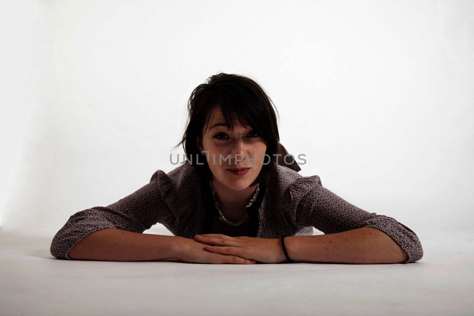 young brunette woman lenthened on the ground isolated in studio looking ahead