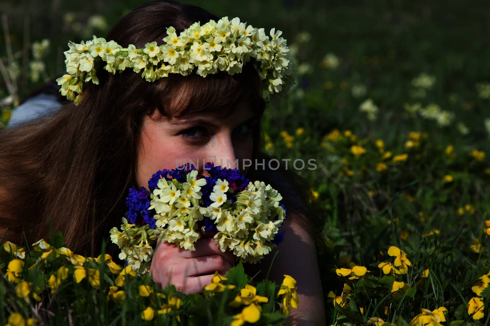 Girl with a wreath and a bouquet of spring on the lawn