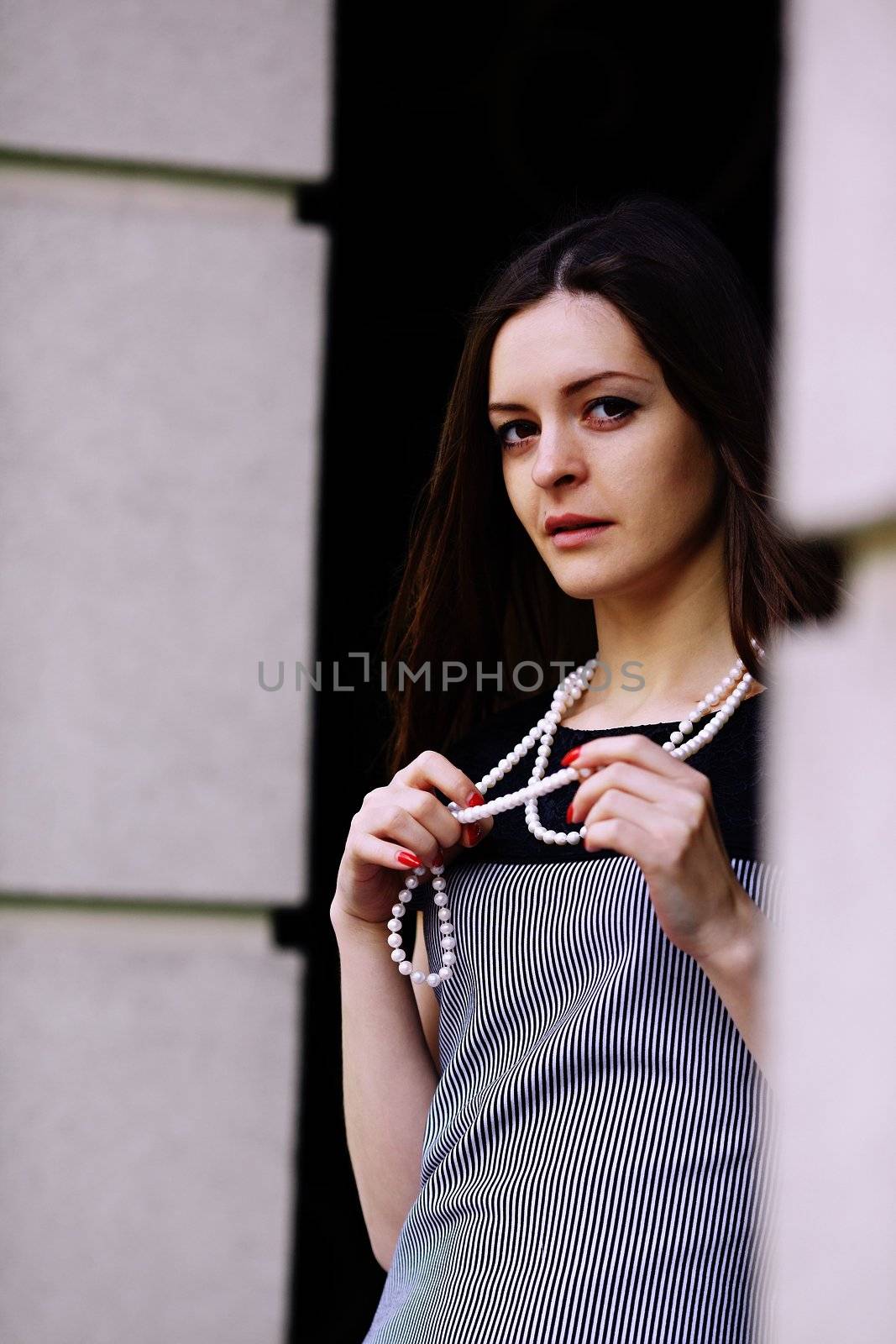 Attractive girl in a beautiful dress, holding in hands white beads