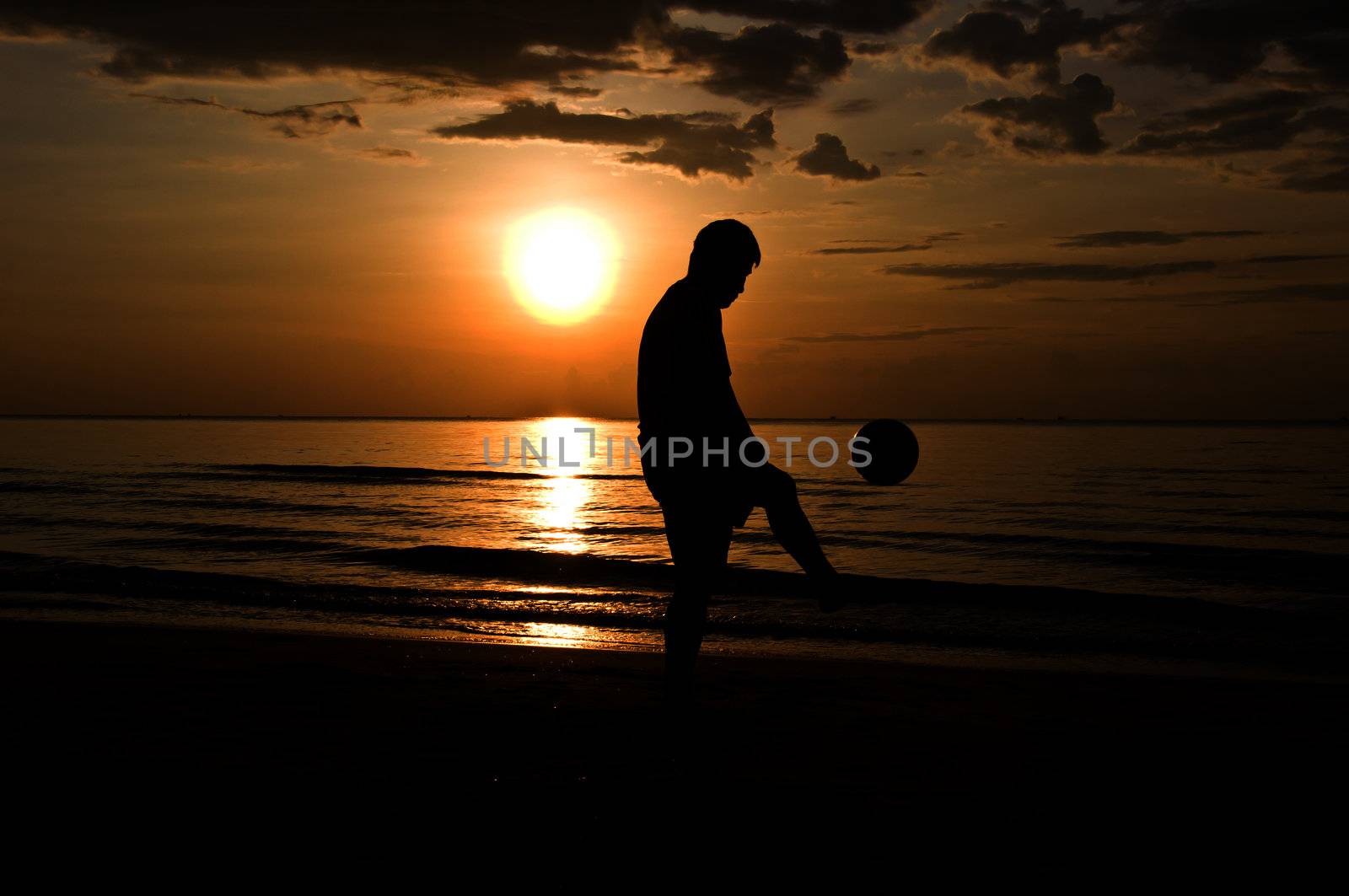 silhouette man playing soccer on the beach