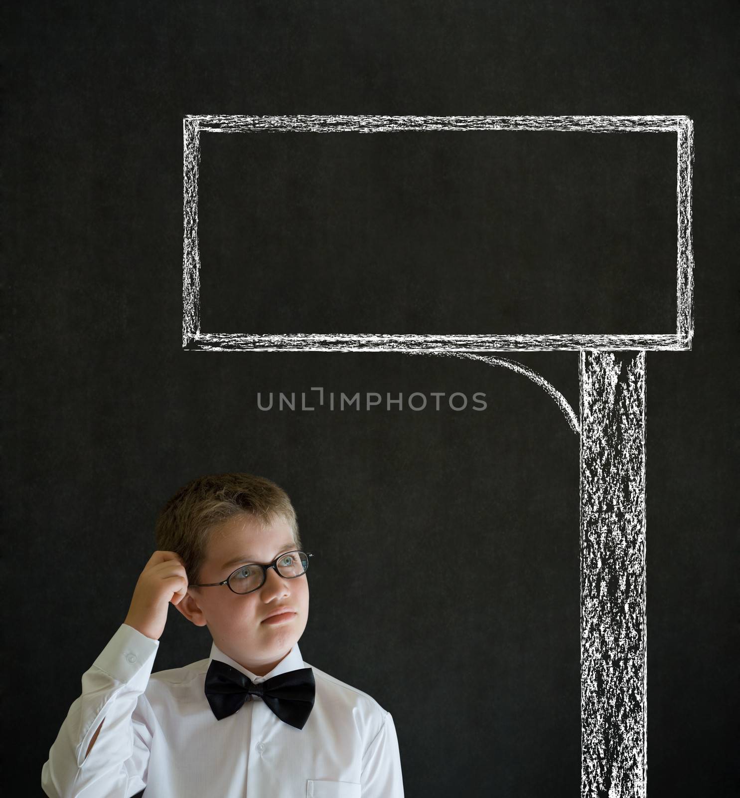 Scratching head thinking boy dressed up as business man with chalk road advertising sign on blackboard background
