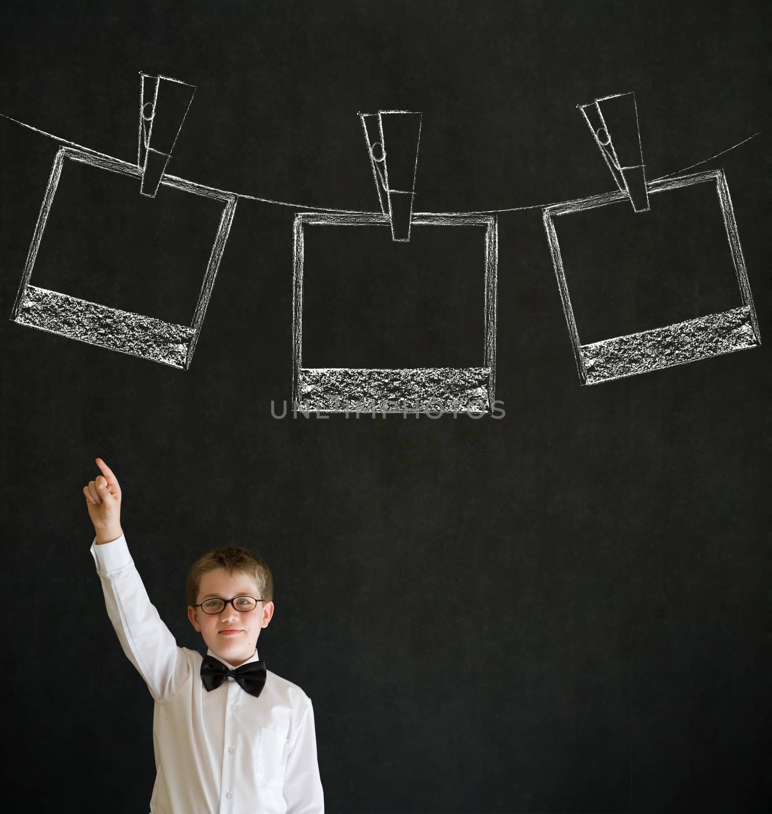 Hand up answer boy dressed up as business man with hanging instant photograph on blackboard background