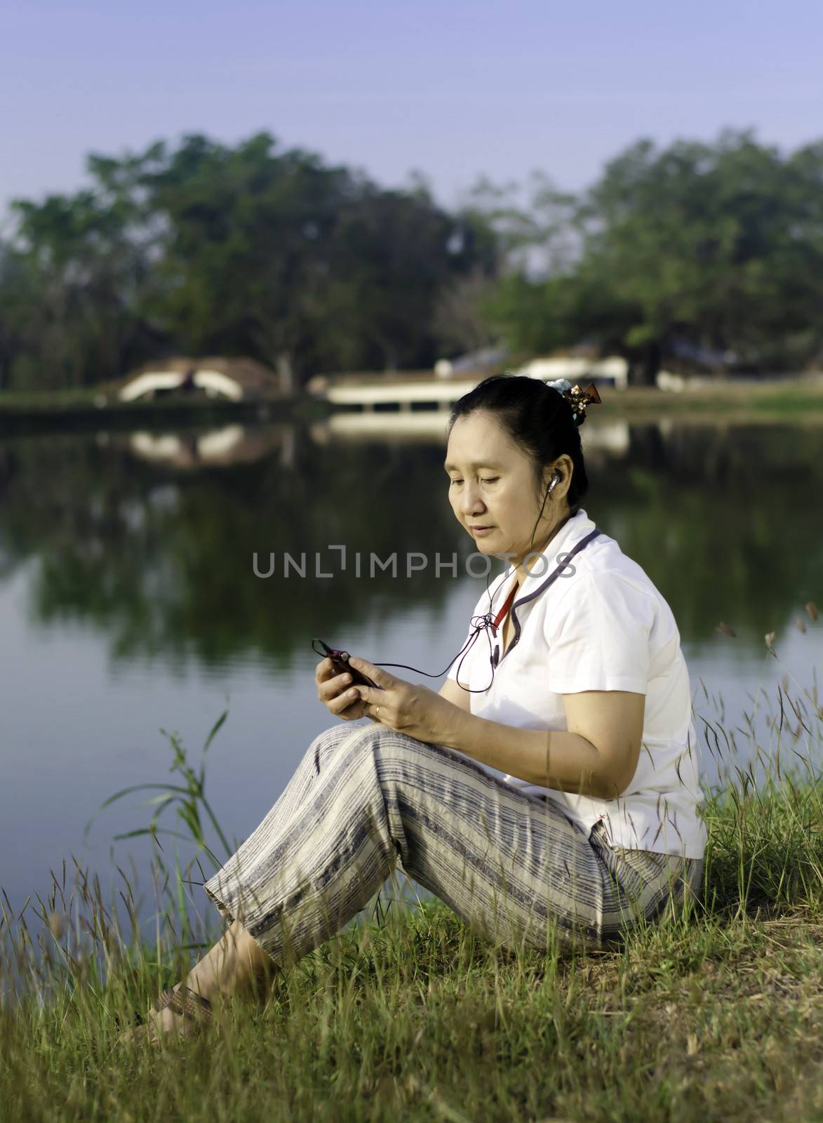 Happy woman on grass listening to music by siraanamwong