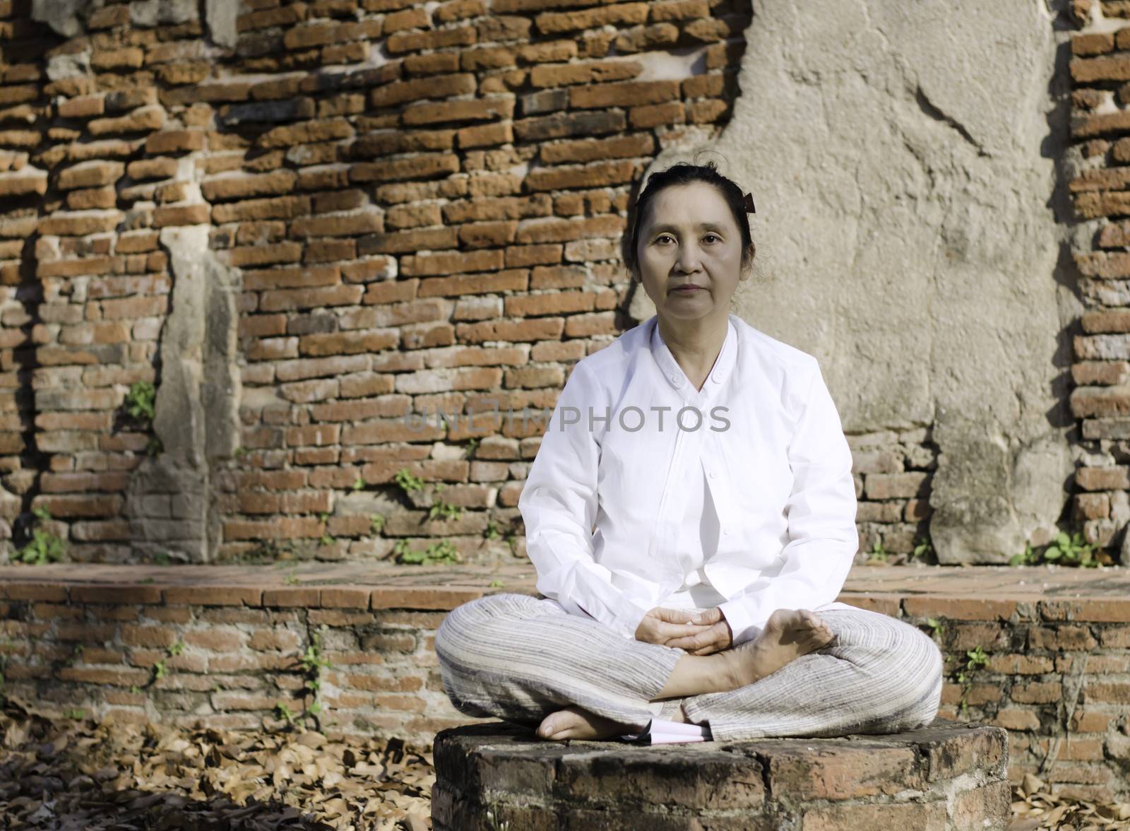 Buddhist woman meditating against ancient temple