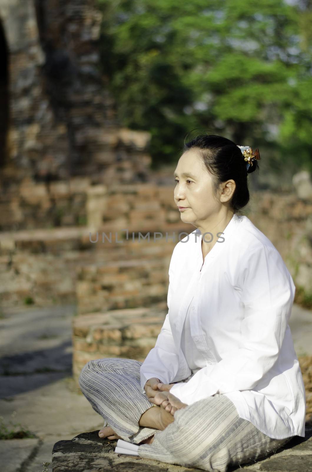 Asian woman meditating yoga in ancient buddhist temple 