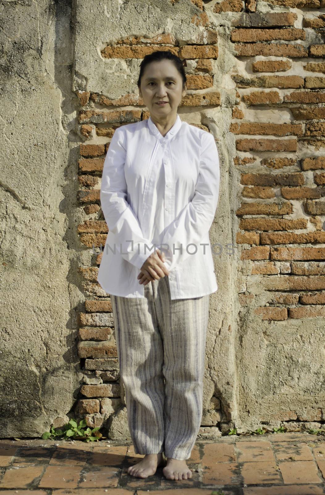 Asian woman standing meditating against ancient temple