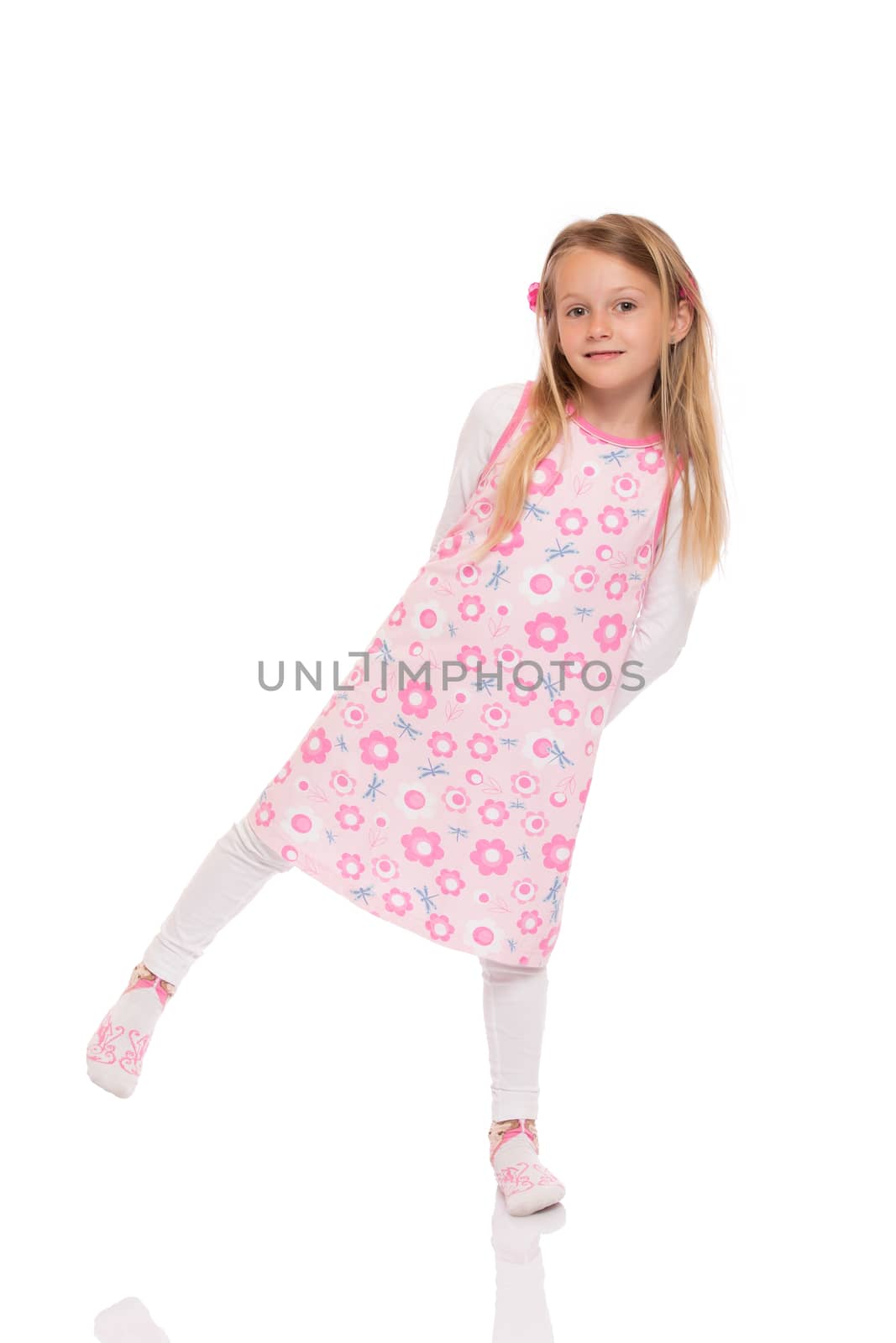 Full length portrait of a little girl with long hair wearing summer dress and balancing at one leg. Isolated on white background.