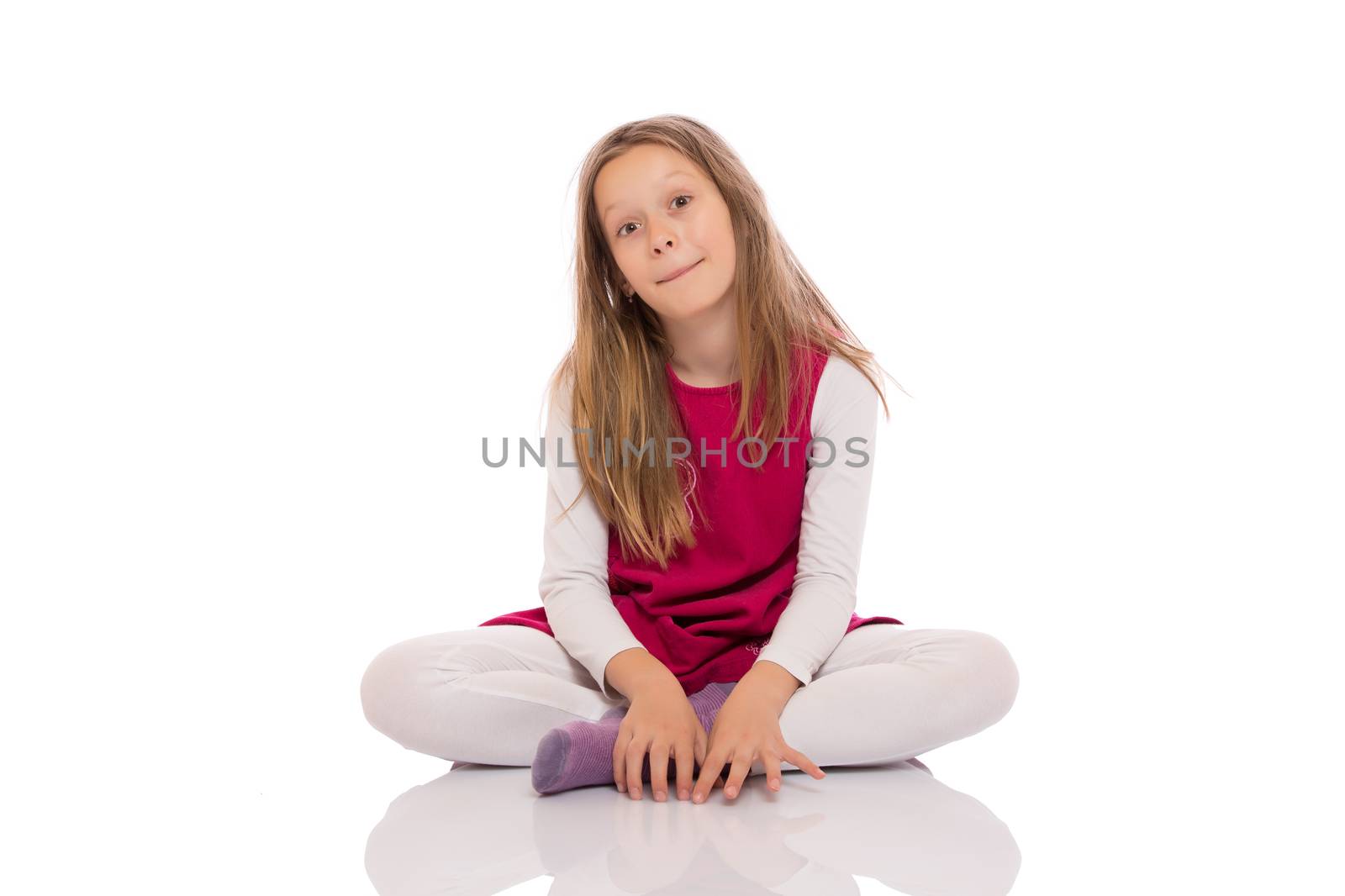 Portrait of a young girl with long hair sitting with crossed legs on the floor and making faces. Isolated on white background.