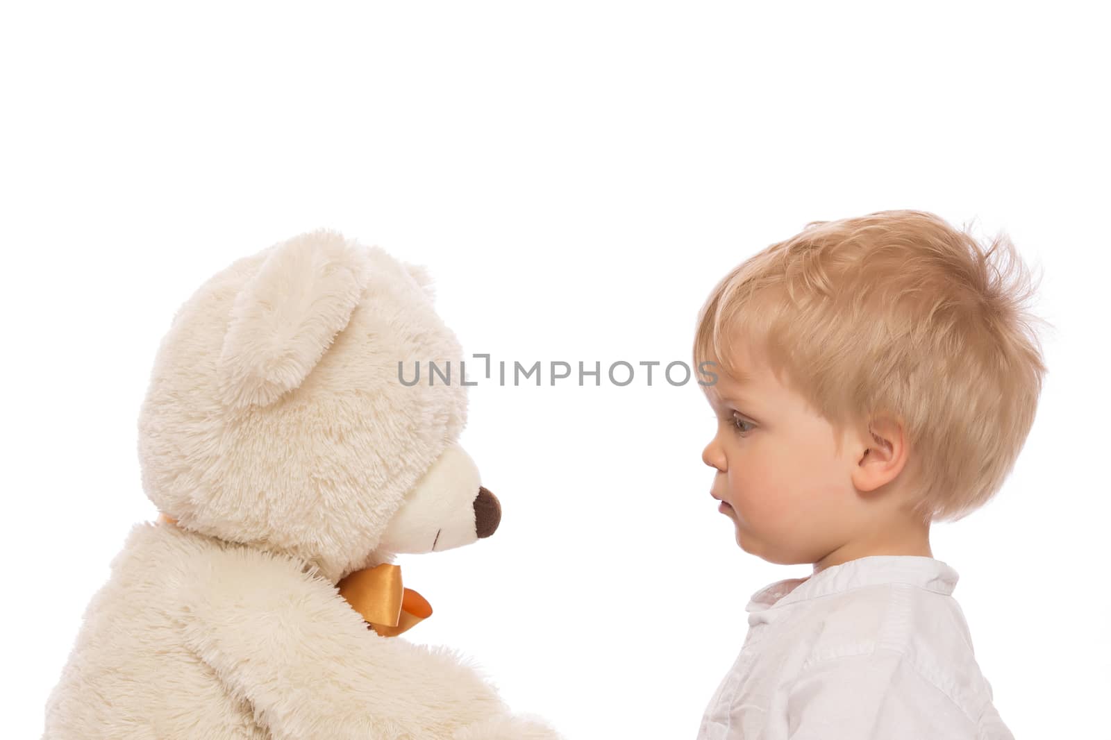 Cute child with blond hair looking her teddy bear. Isolated on white background.