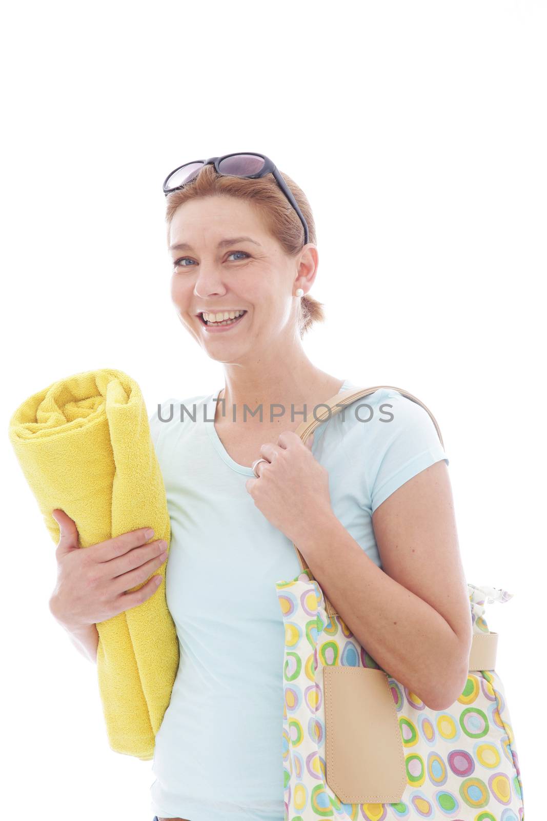 Smiling woman in glasses goes to the beach with bag and towel