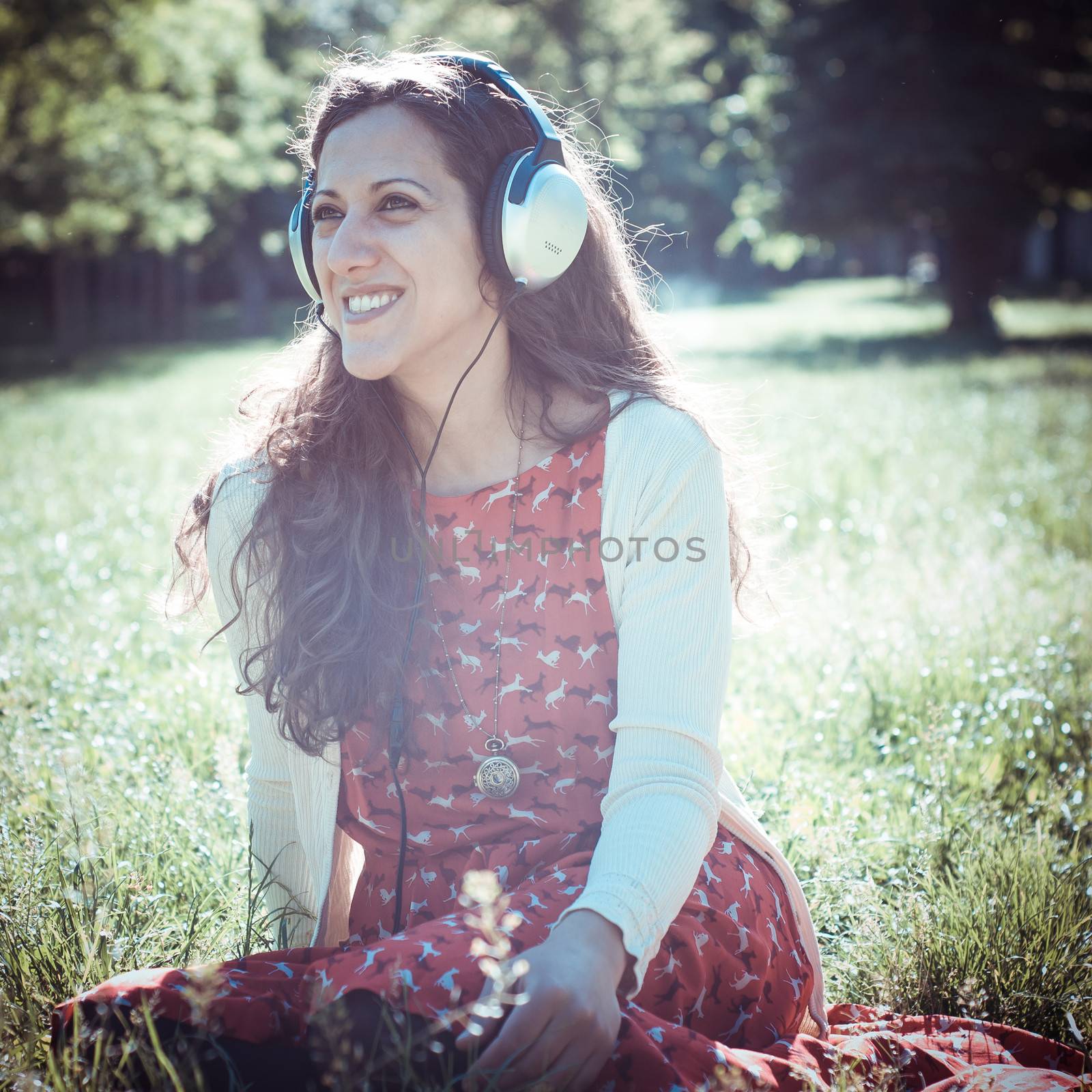 vintage hipster eastern woman with headphones in the park