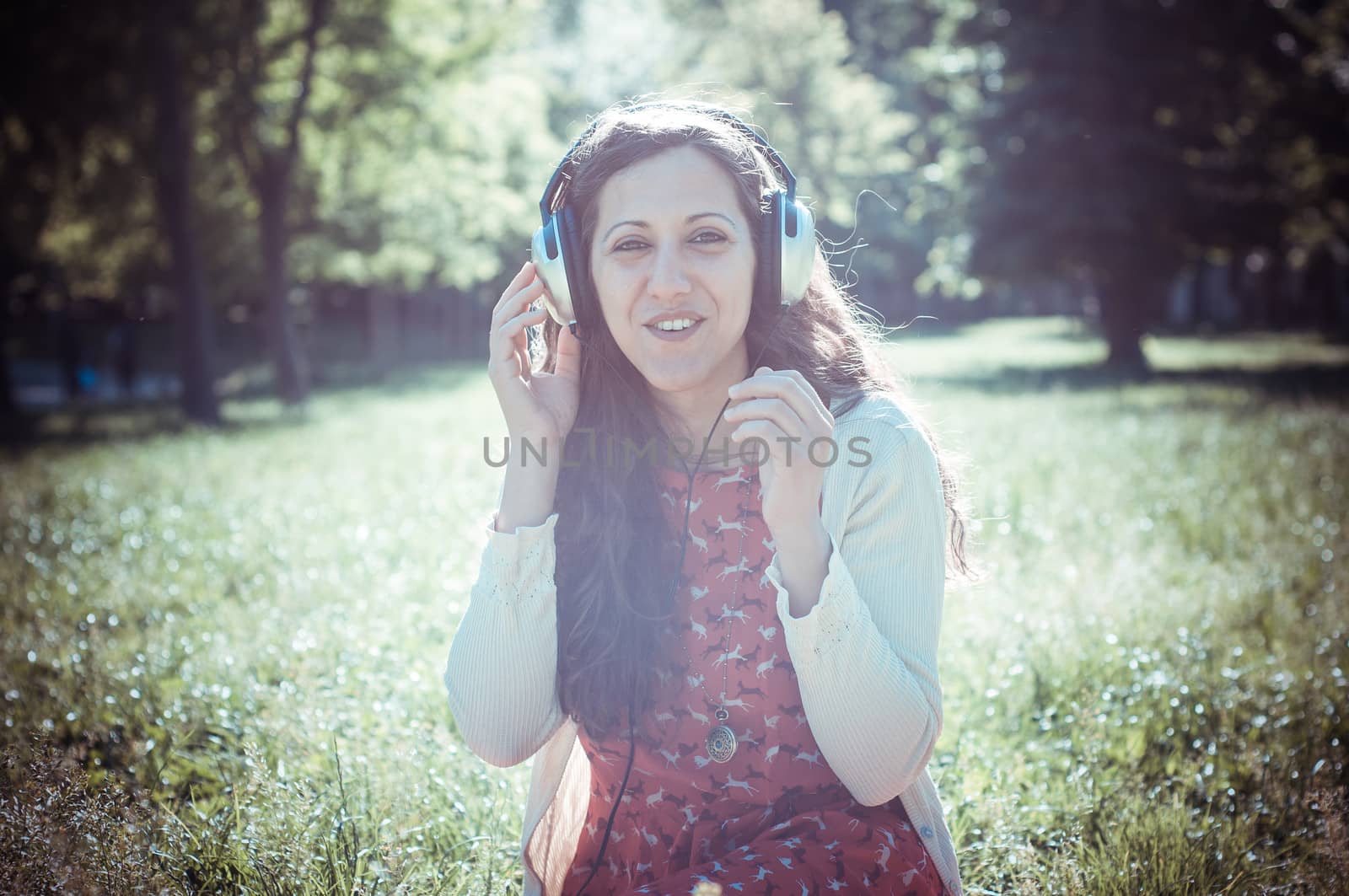 vintage hipster eastern woman with headphones in the park