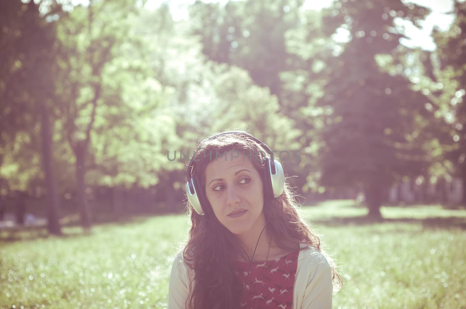 vintage hipster eastern woman with headphones in the park