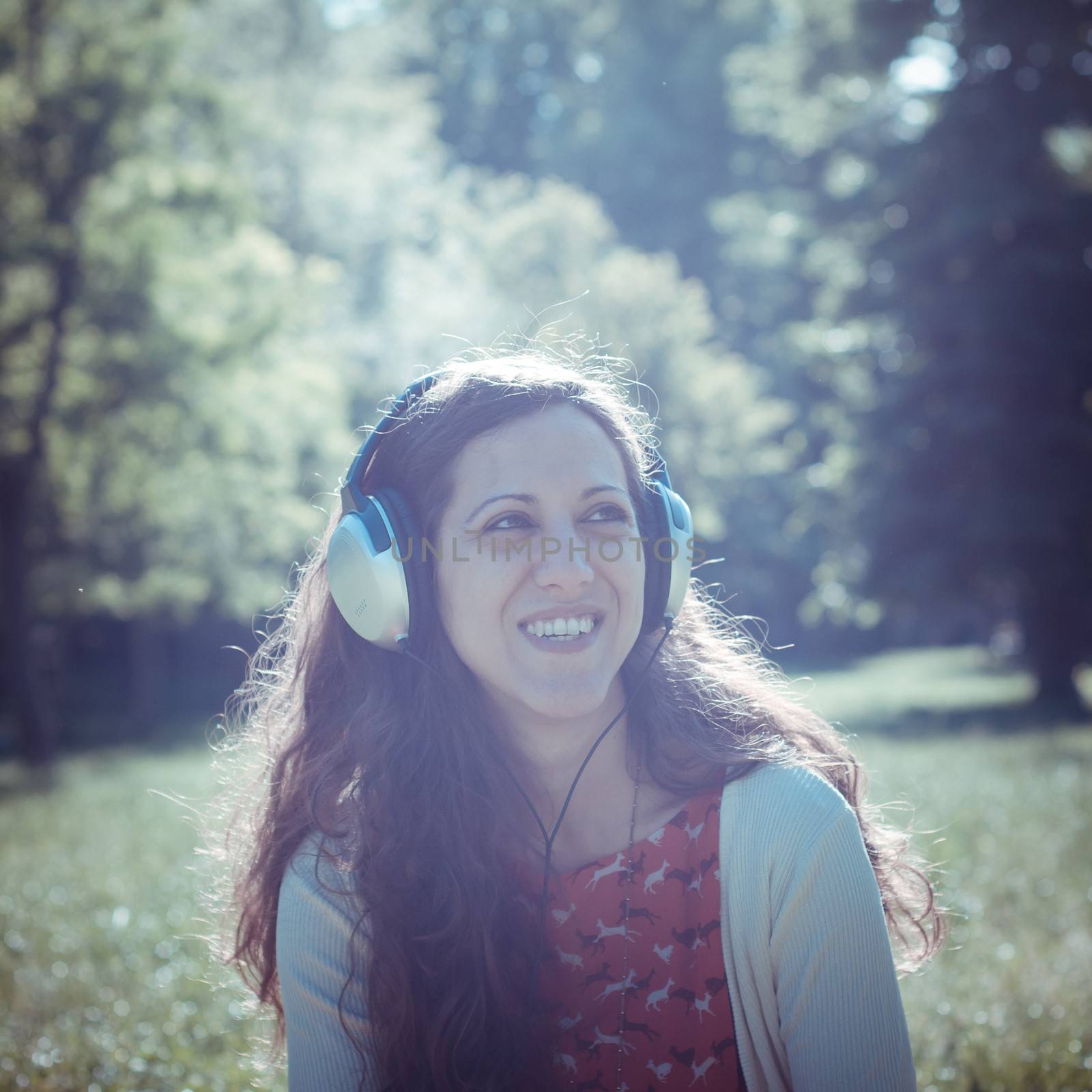 vintage hipster eastern woman with headphones in the park