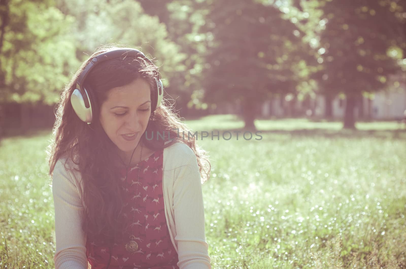 vintage hipster eastern woman with headphones in the park