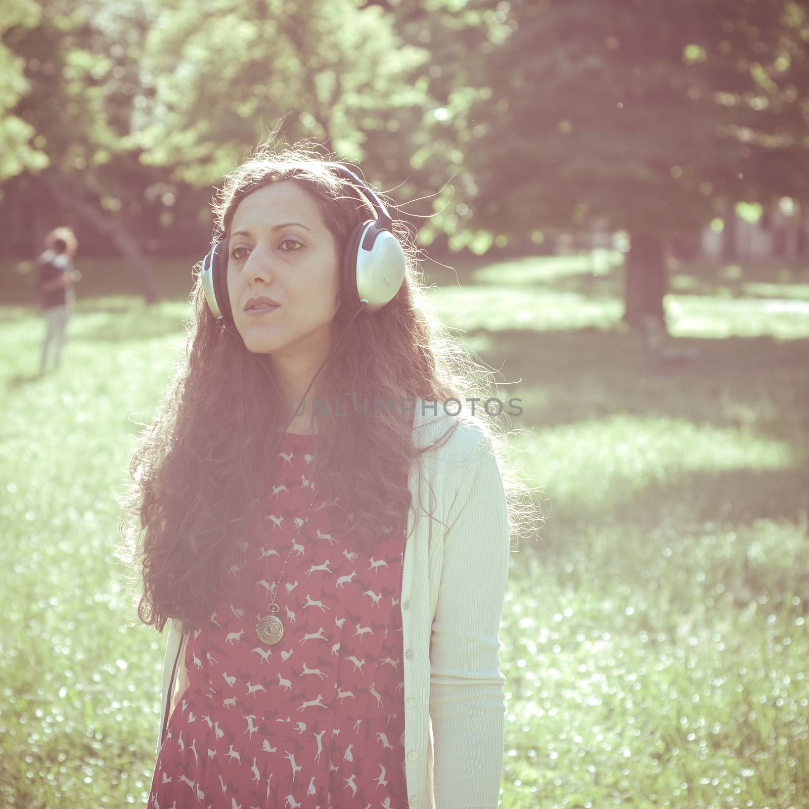 vintage hipster eastern woman with headphones in the park