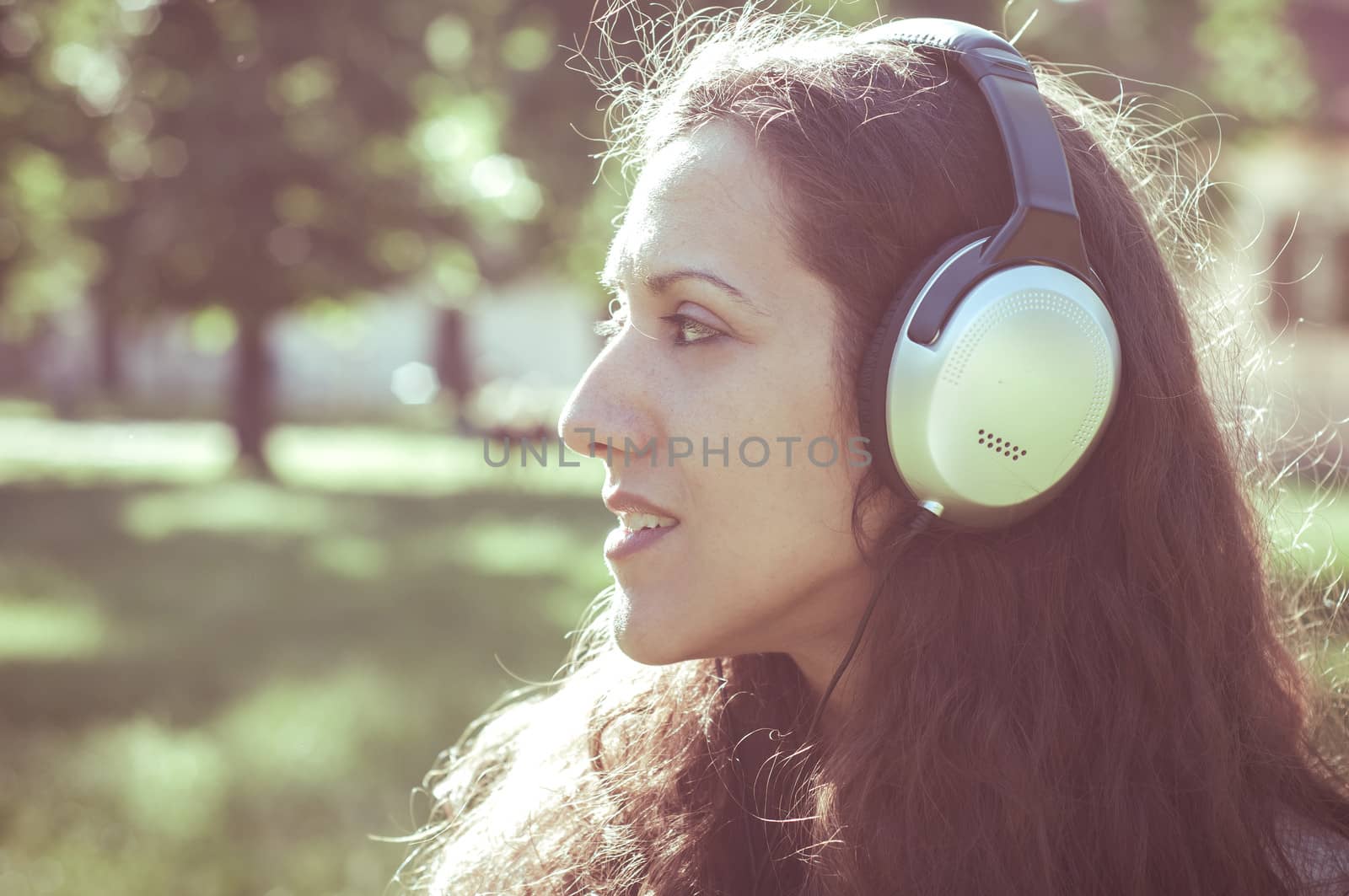 vintage hipster eastern woman with headphones in the park