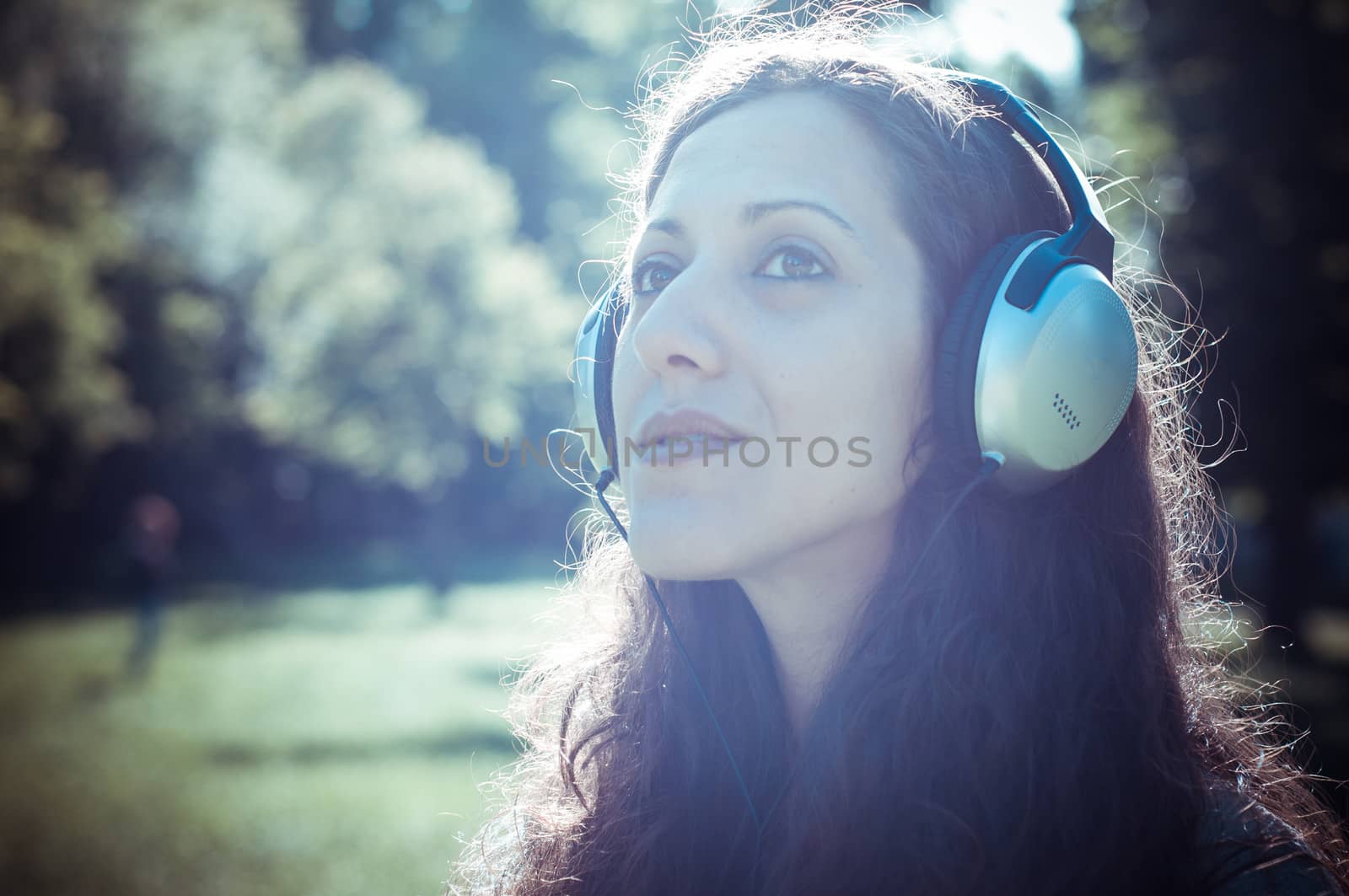 vintage hipster eastern woman with headphones in the park