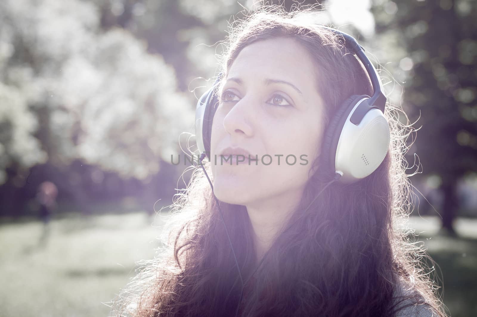 vintage hipster eastern woman with headphones in the park