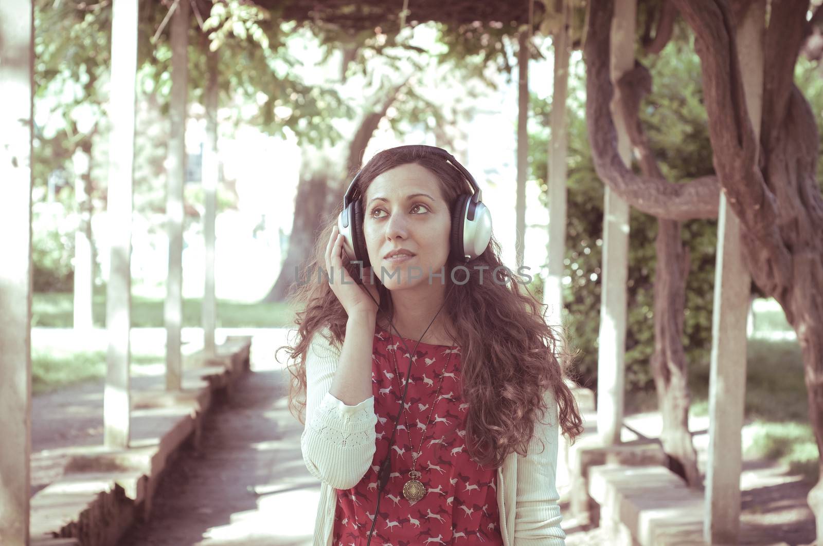 vintage hipster eastern woman with headphones in the park