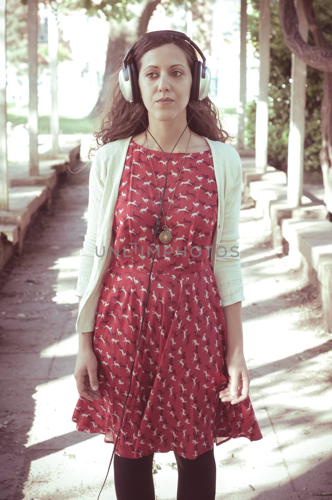 vintage hipster eastern woman with headphones in the park