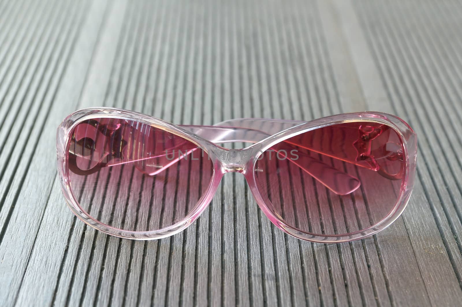 Pink sunglasses put on the wooden table