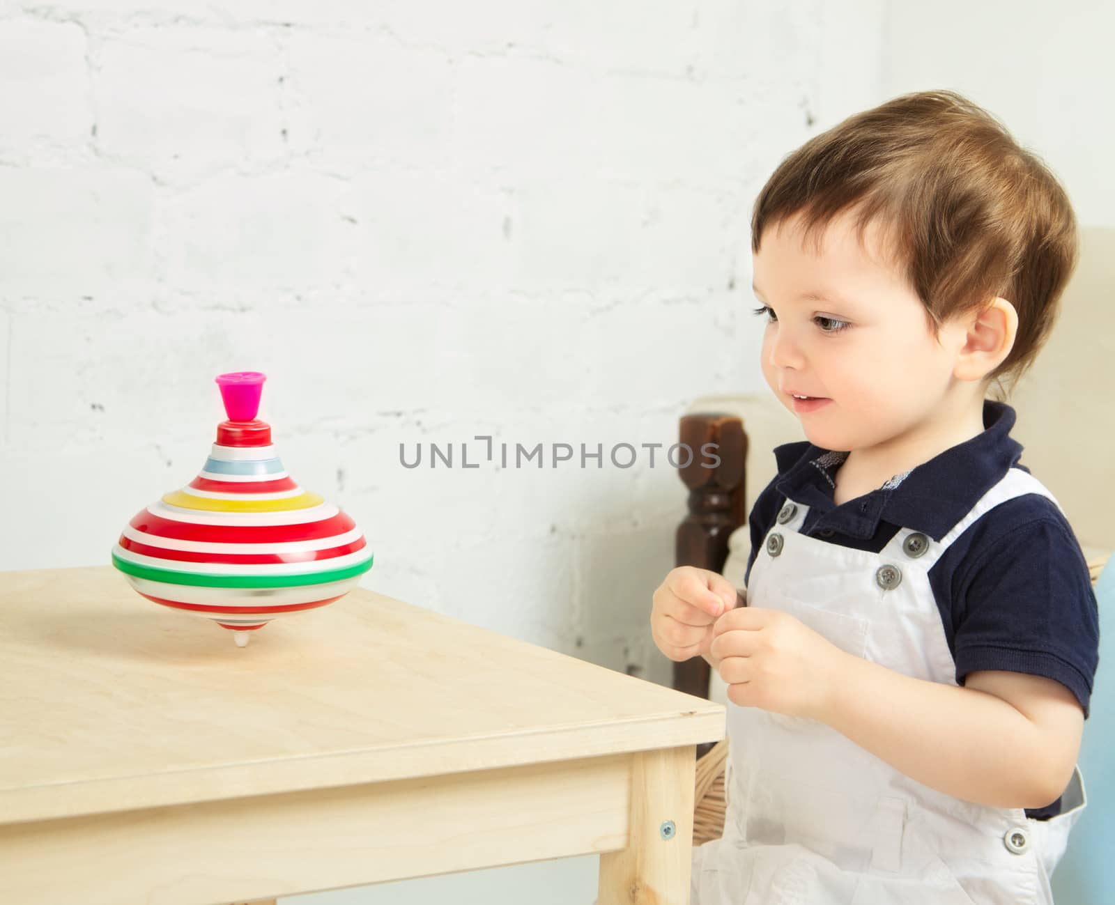 little boy playing with whirligig on a table