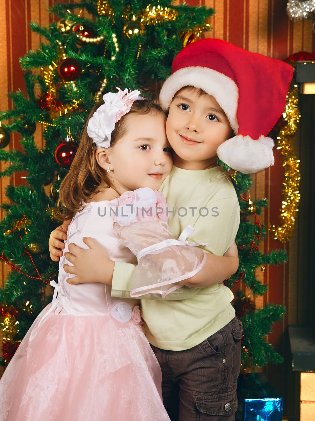 two beautiful child stand near christmas tree