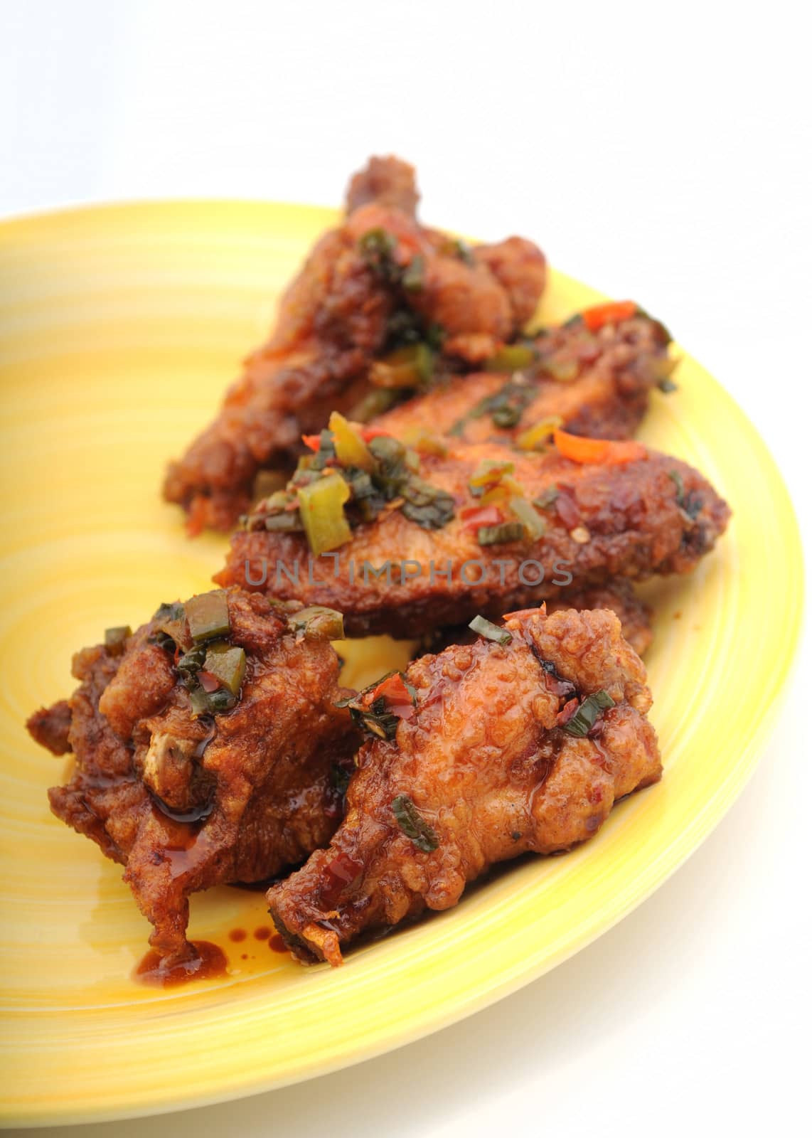 half dozen chicken wings with peppers and seasoning on yellow plate