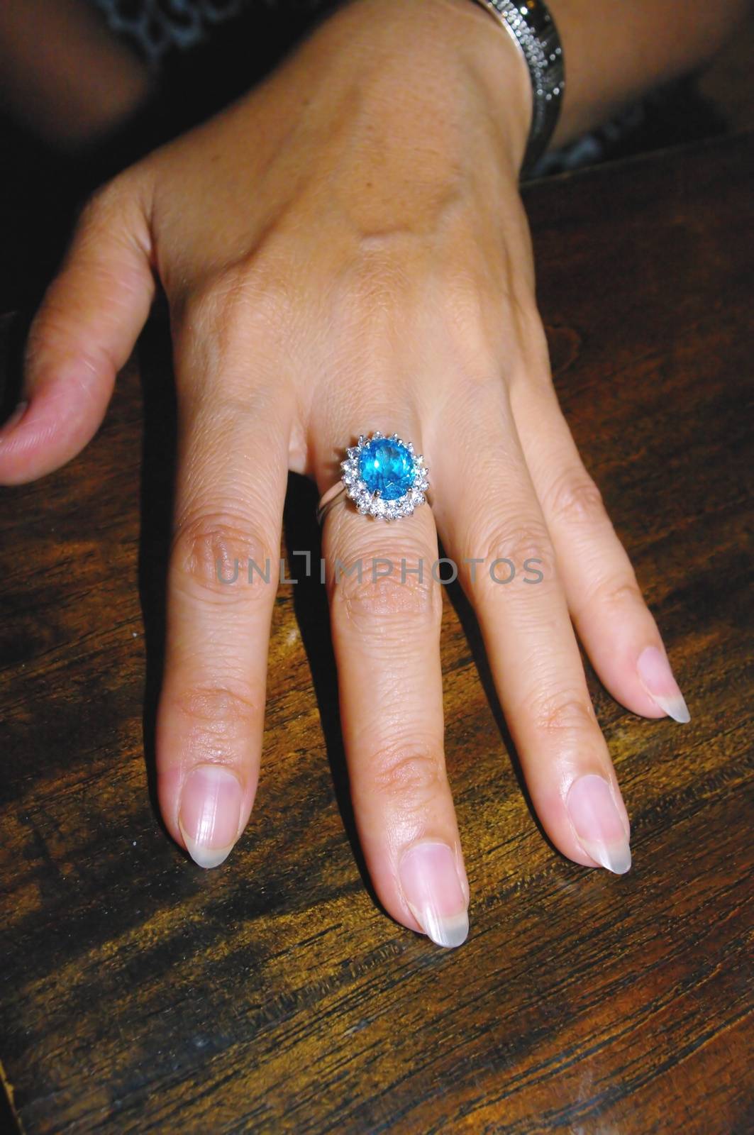 A woman's hand with an engagement ring. A topaz surrounded by diamonds on white gold setting