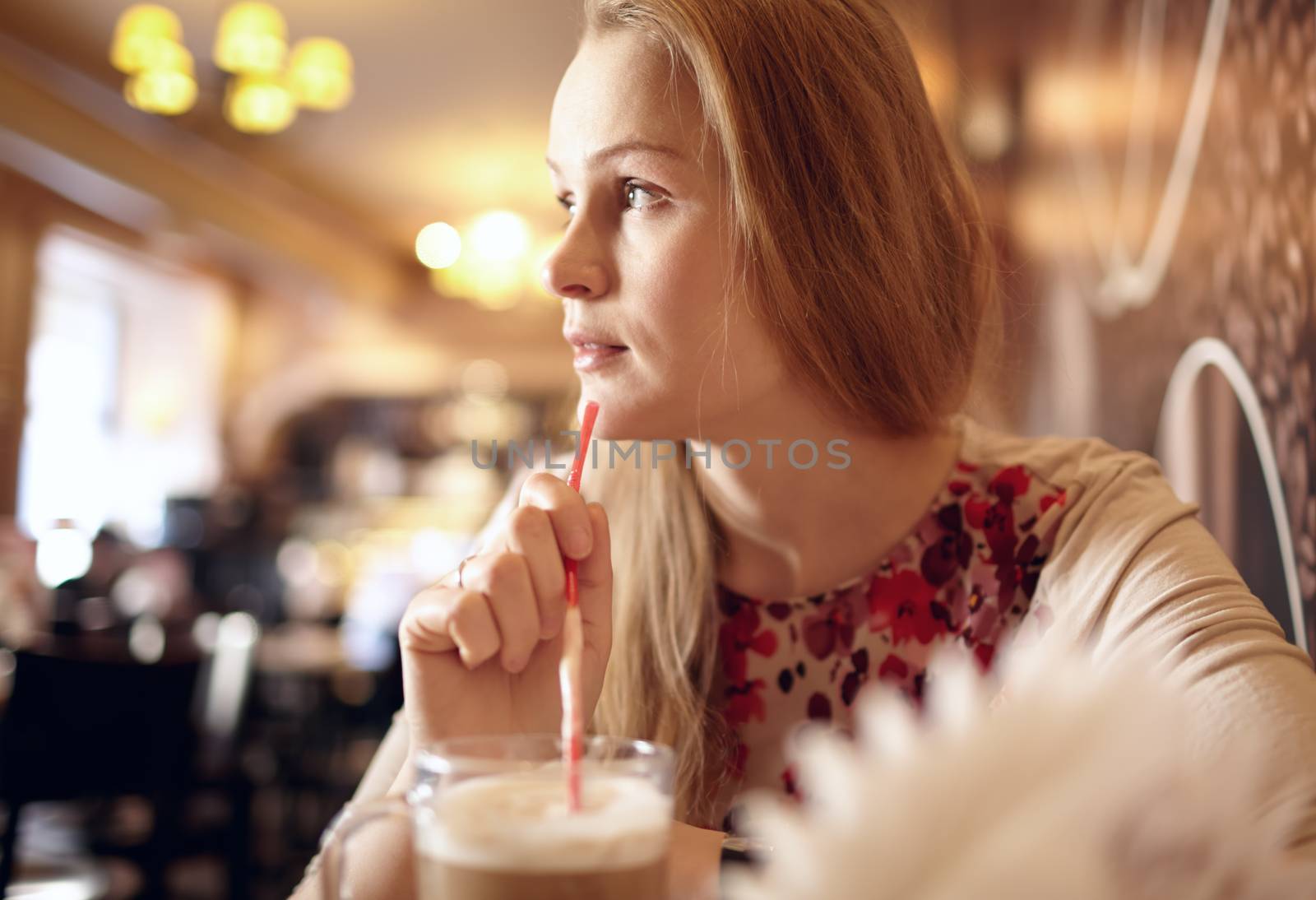 Portrait of girl enjoying coffee in cafe and looking through the window. Beautiful vintage interior in blur with natural sunlight.