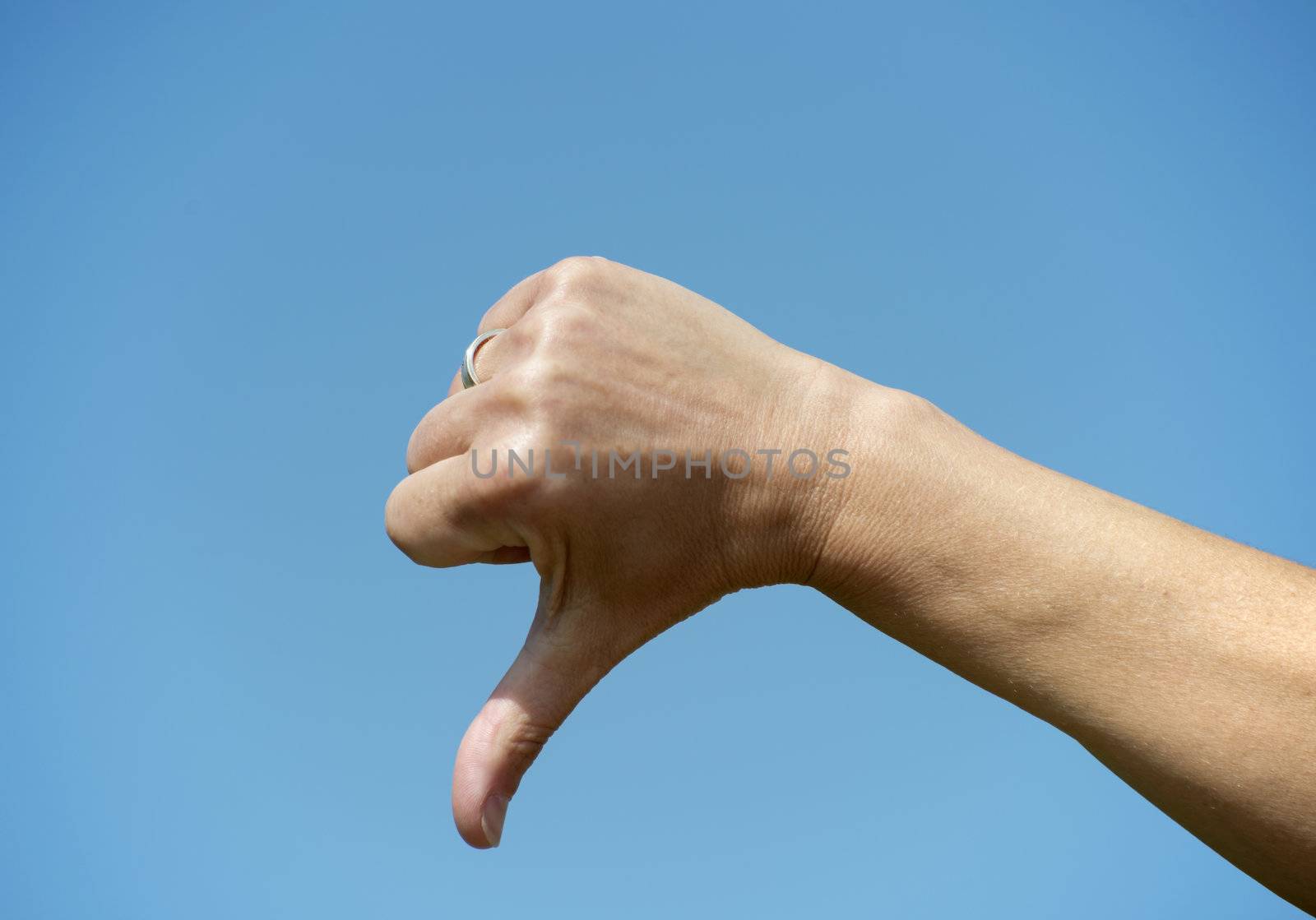 female thumb down on blue sky