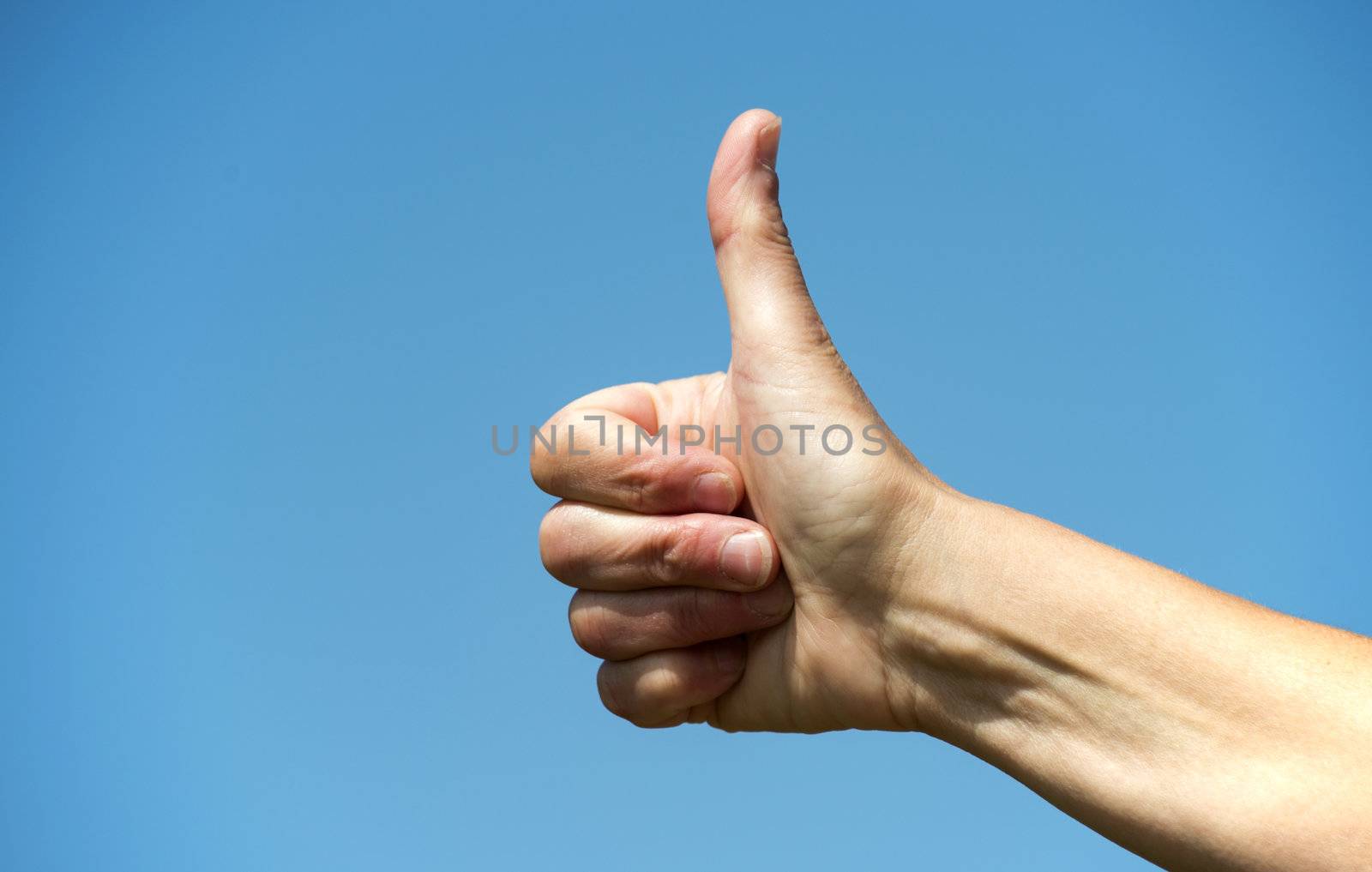 female hand with thumb up on blue sky