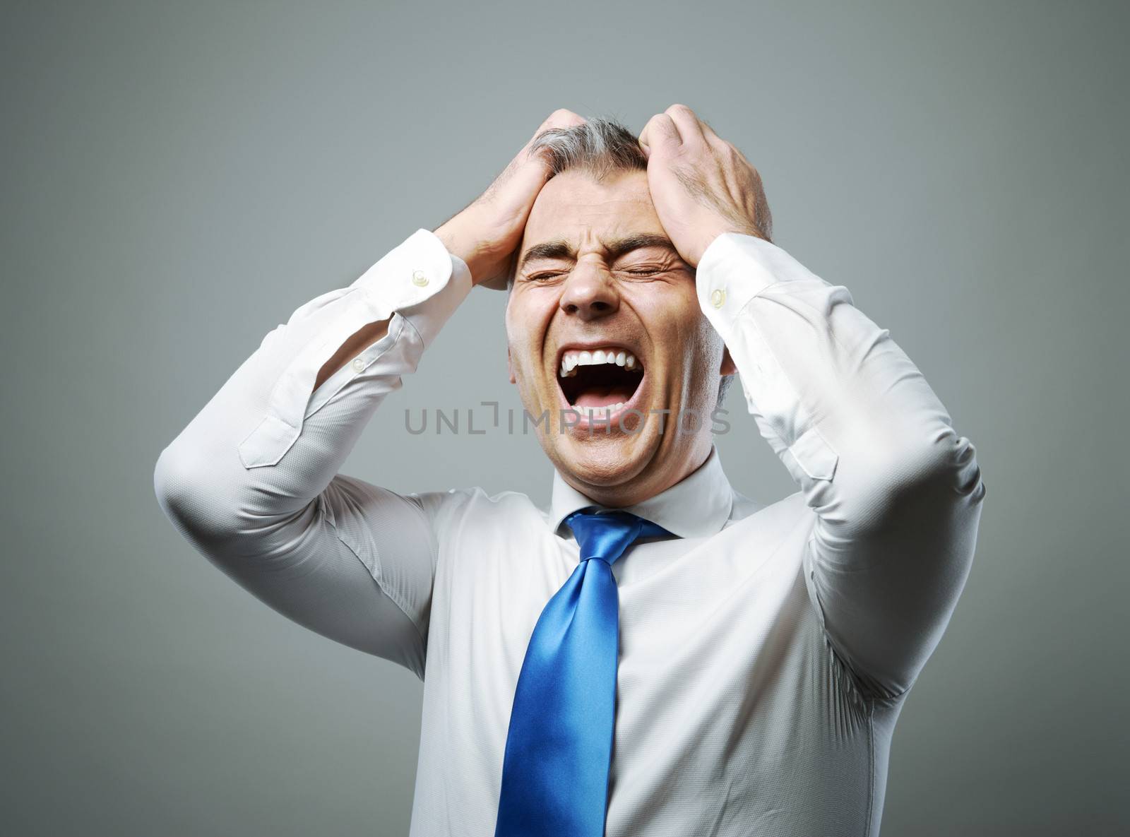 Frustrated mature businessman with his hands on his head while yelling