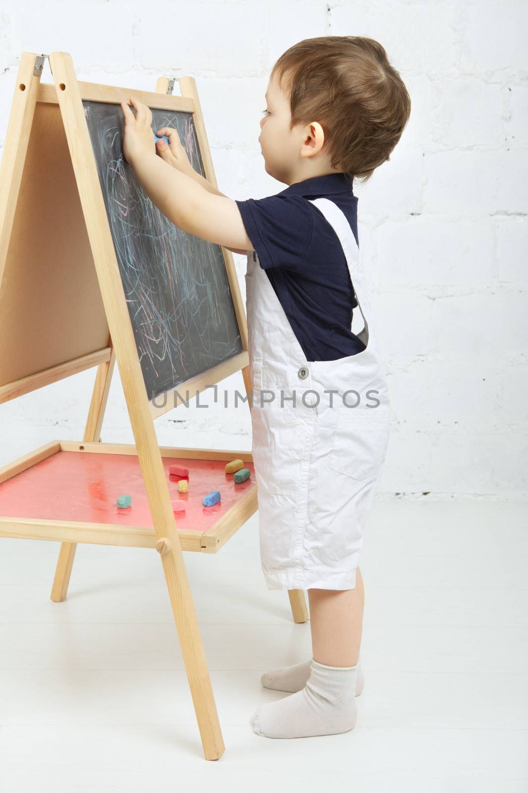 little boy drawing with chalk at blackboard