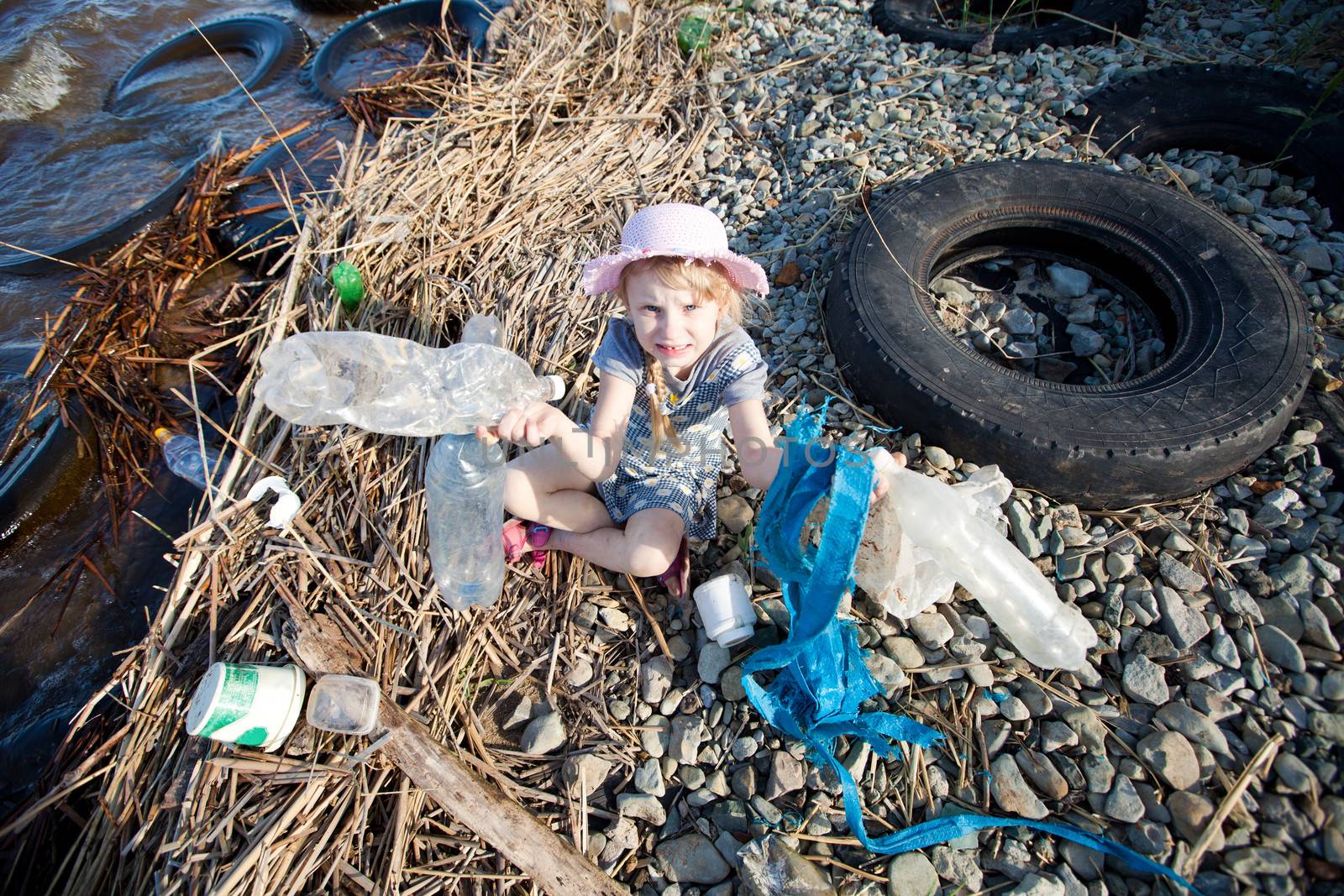 small girl collecting rubbish near the river