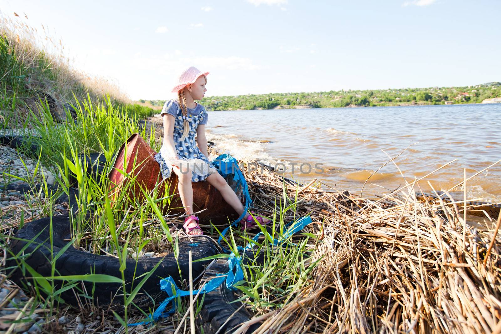 small girl on the bank of river with rubbish by vsurkov