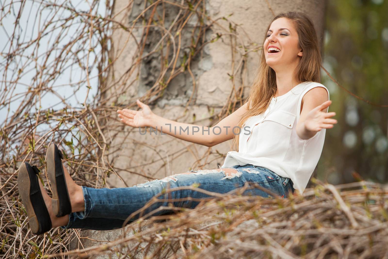 Beautiful caucasian woman in casual sitting next to the old vine with open hands