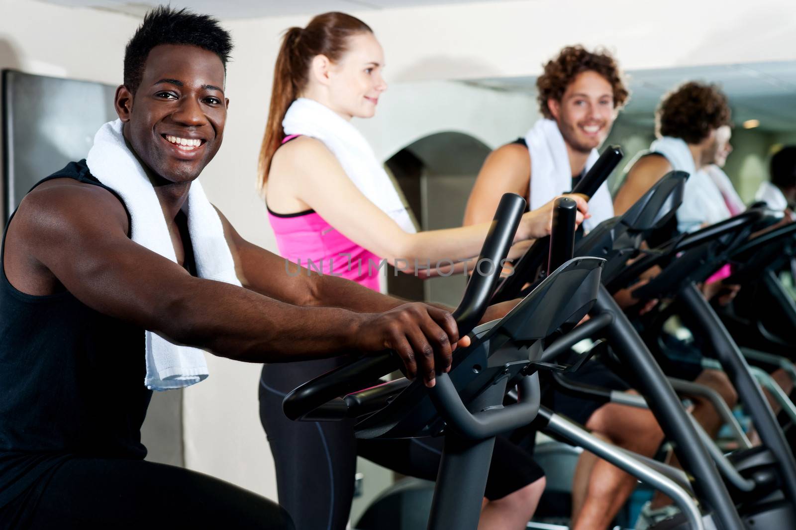 Group of smiling people at the gym doing cardio exercise
