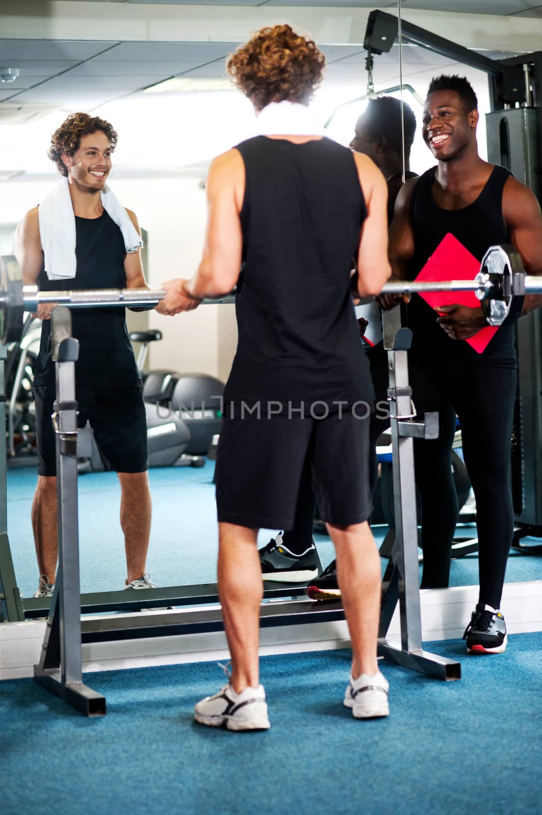 Young man with his trainer in gym, lifting barbells