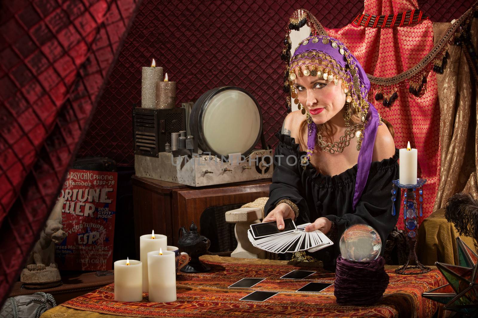 Smiling gypsy soothsayer with hand of tarot cards