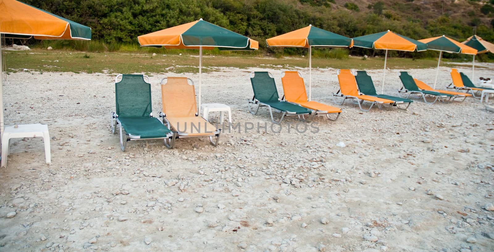 Beach lounge chairs under shade of umbrellas . by LarisaP