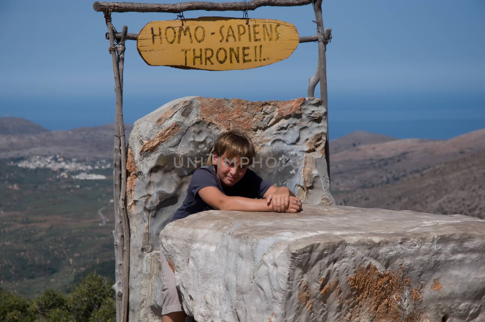 Boy sits on the throne of mountains in the background. Crit. Greece.