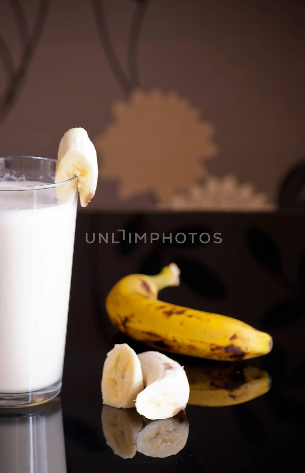 fresh banana smoothie and fruits on black background