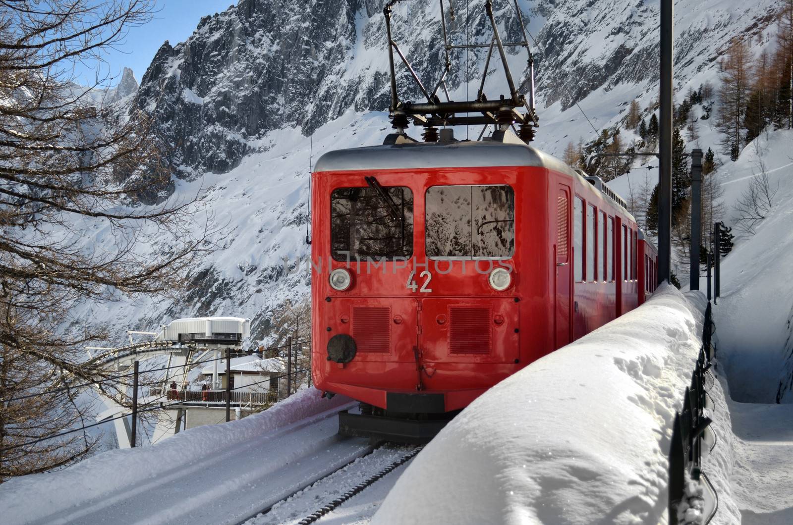 Small, red mountain train climbing railway in the snow