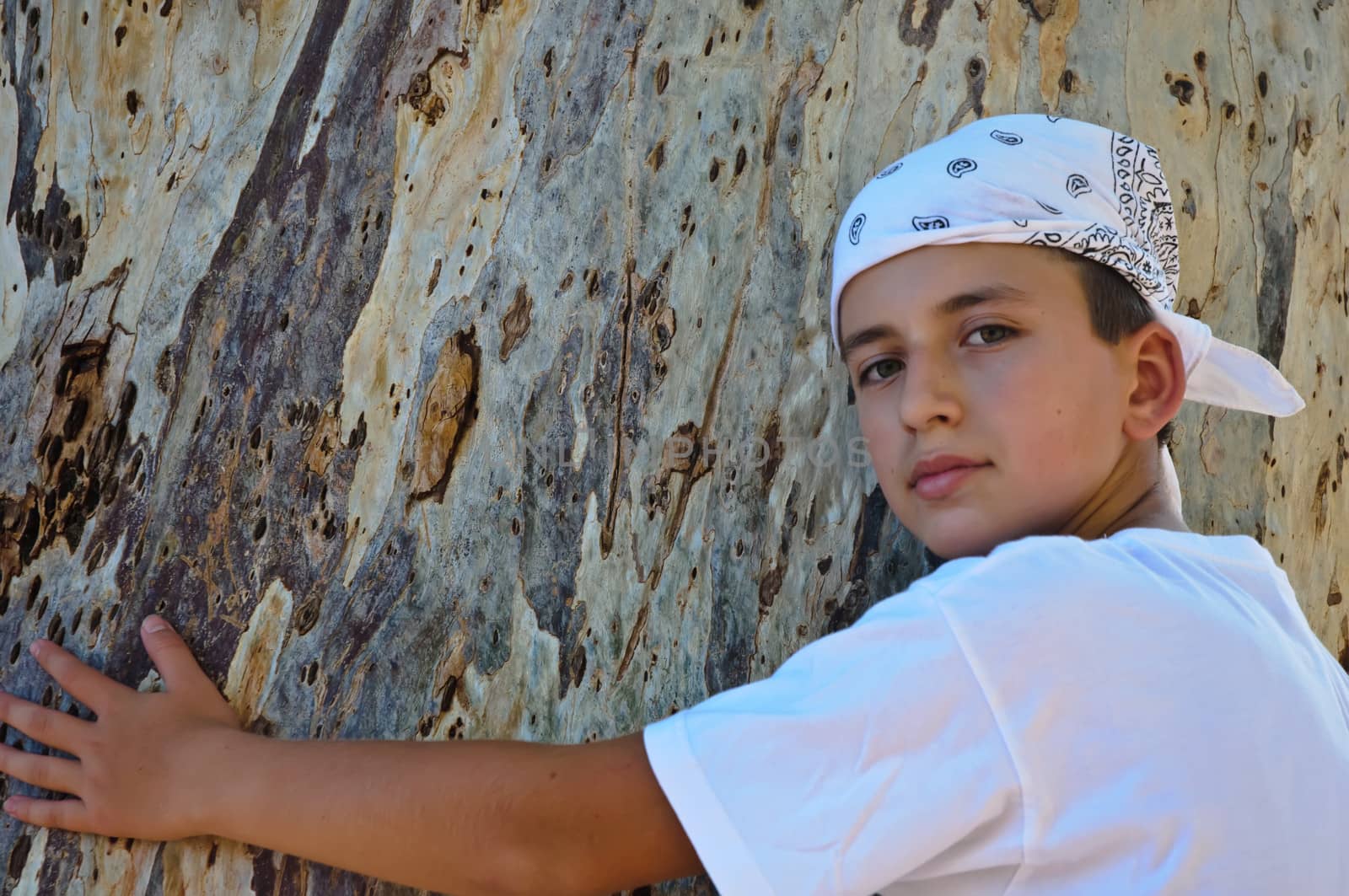 Portrait of a Boy in the bandana on the background of the trunk of eucalyptus.