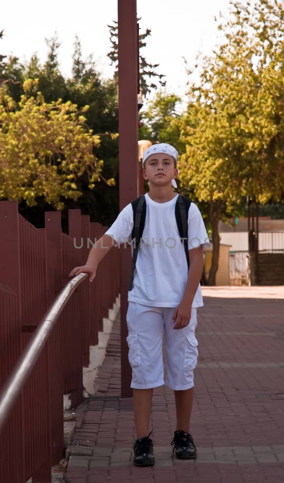 Portrait of a Boy in the bandana and a backpack on his shoulders, iduschna background beige walls.